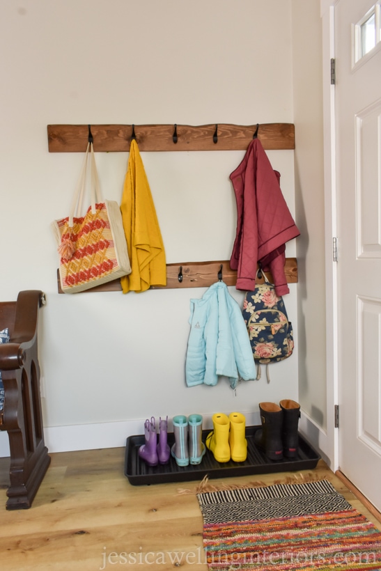 entryway with wall-mounted coat racks and a boot tray