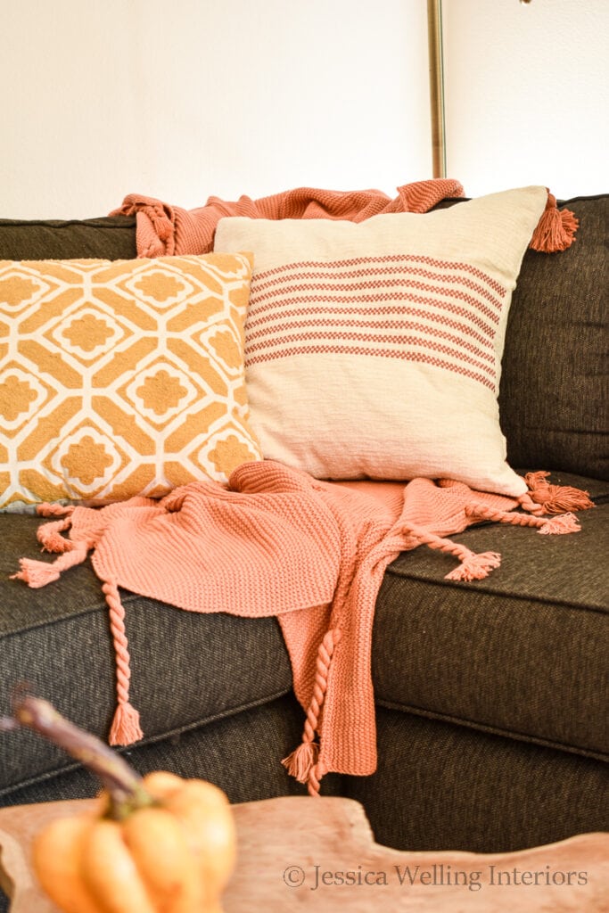 orange fall throw blanket and two throw pillows on a sofa