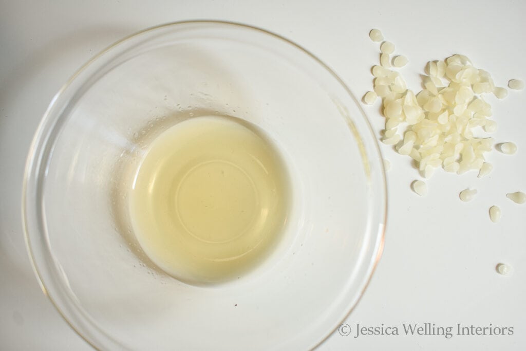 white beeswax pastilles next to a glass bowl of melted white beeswax