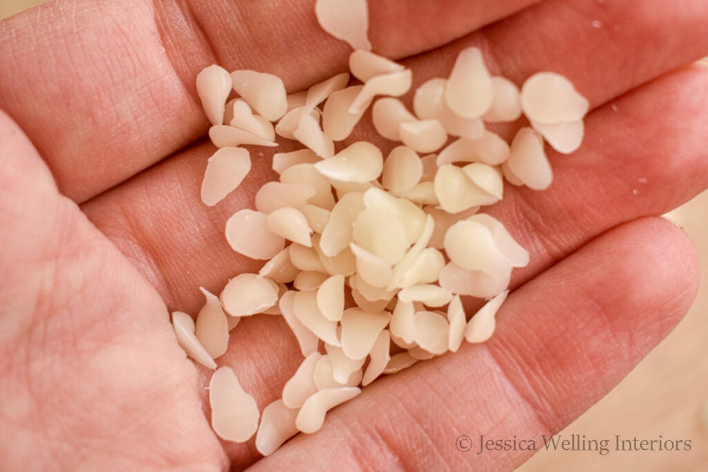 close up of a hand holding a few white beeswax pastilles