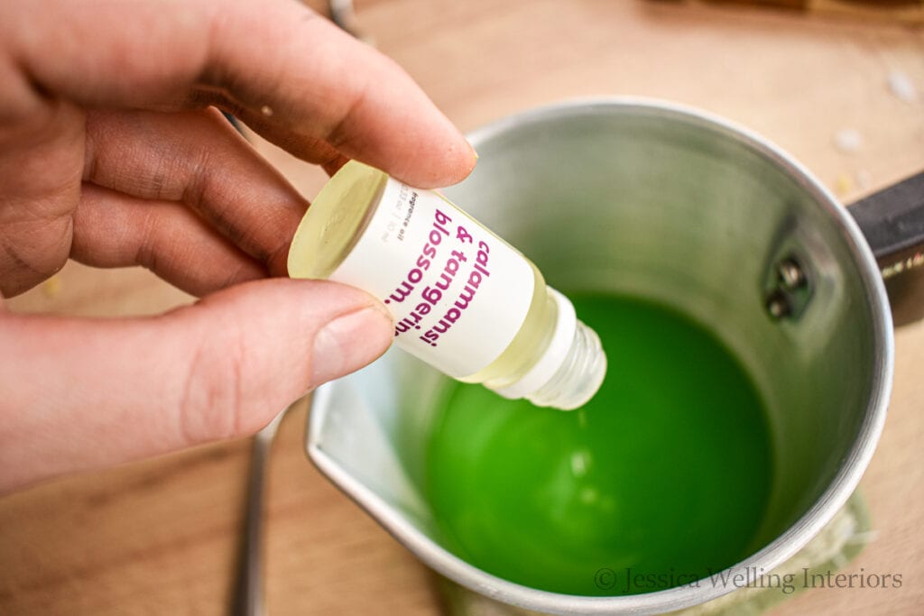 fragrance oil being poured into pitcher of hot wax to make wax melts