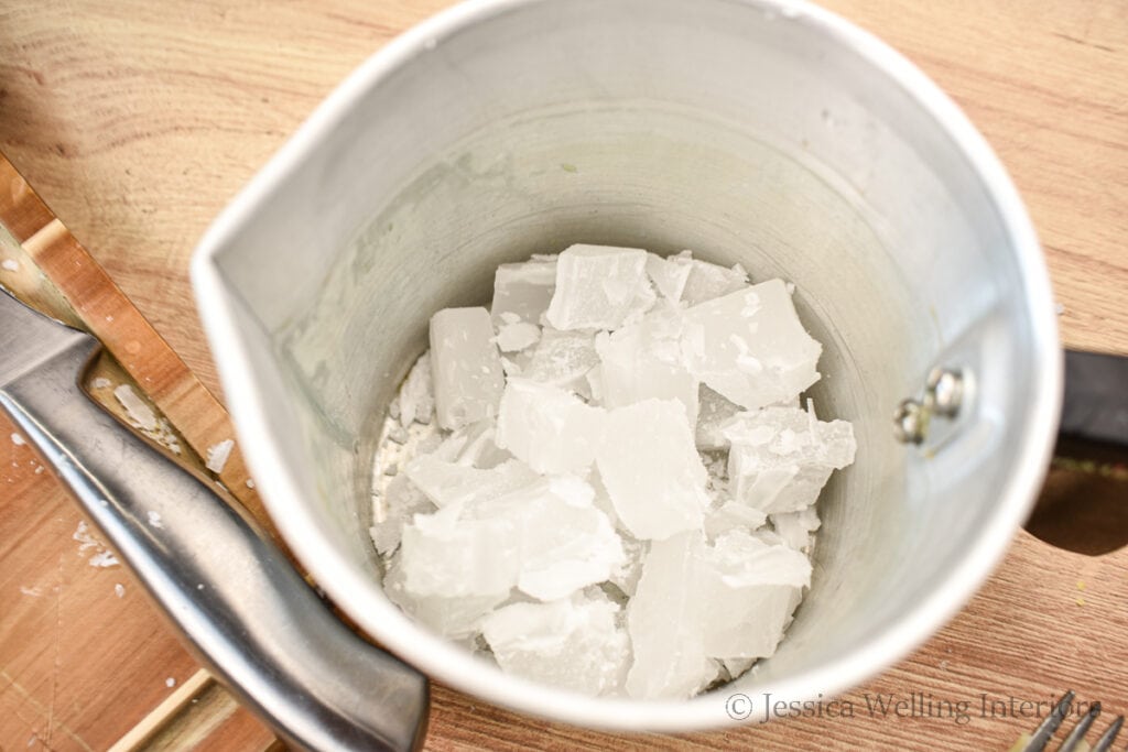 overhead view of a metal pitcher filled with chunks of paraffin wax, ready to be melted