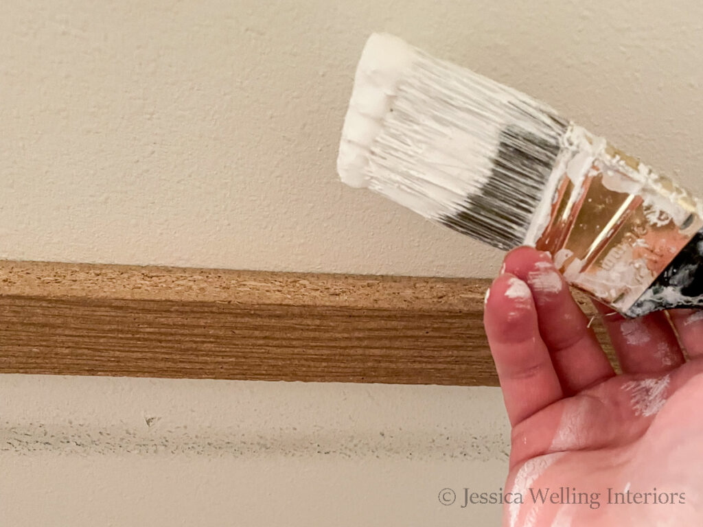 close-up of a hand holding a paintbrush to paint the inside of a deep pantry
