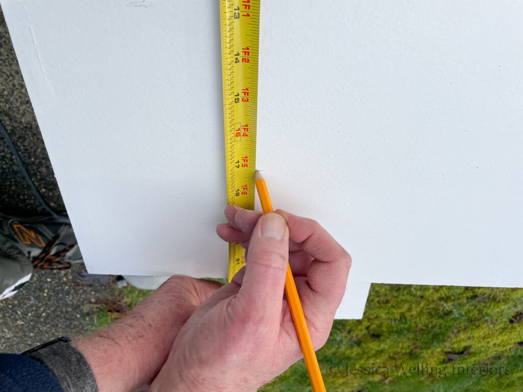 hand holding a tape measure to mark a line on a deep pantry shelf