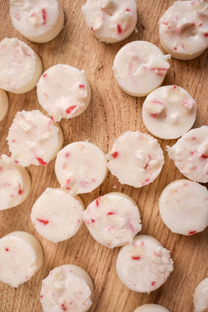 white peppermint scented wax melts with bits of candy cane on a wood background