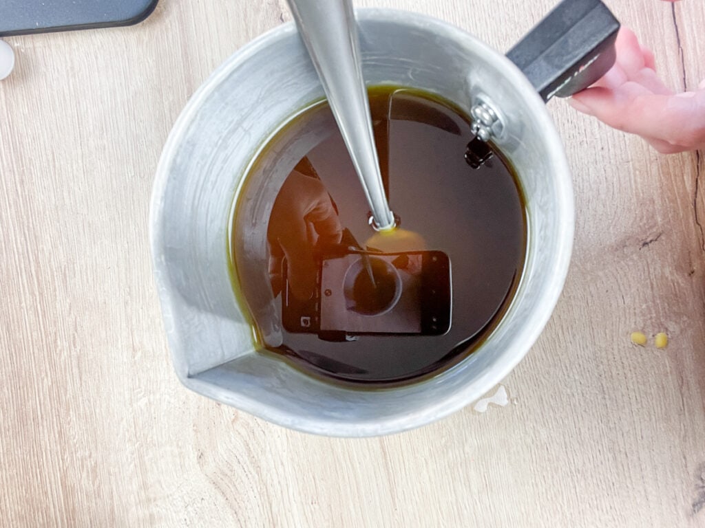 pitcher of melted beeswax being stirred with a fork