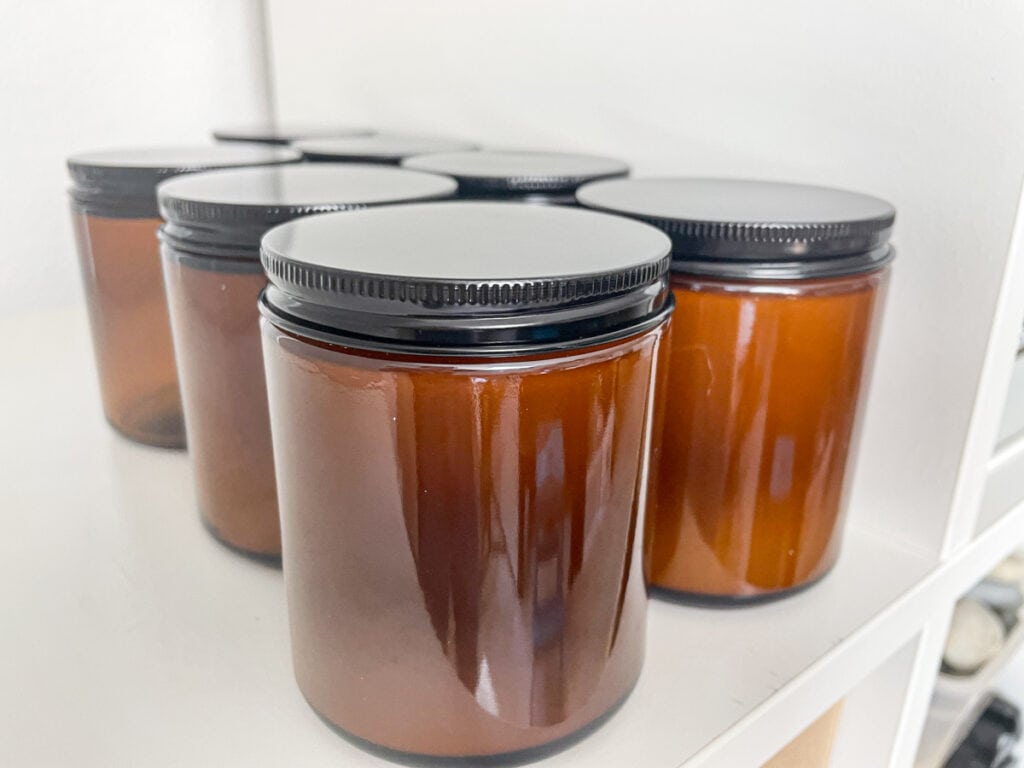 container soy candles with lids on curing on a shelf