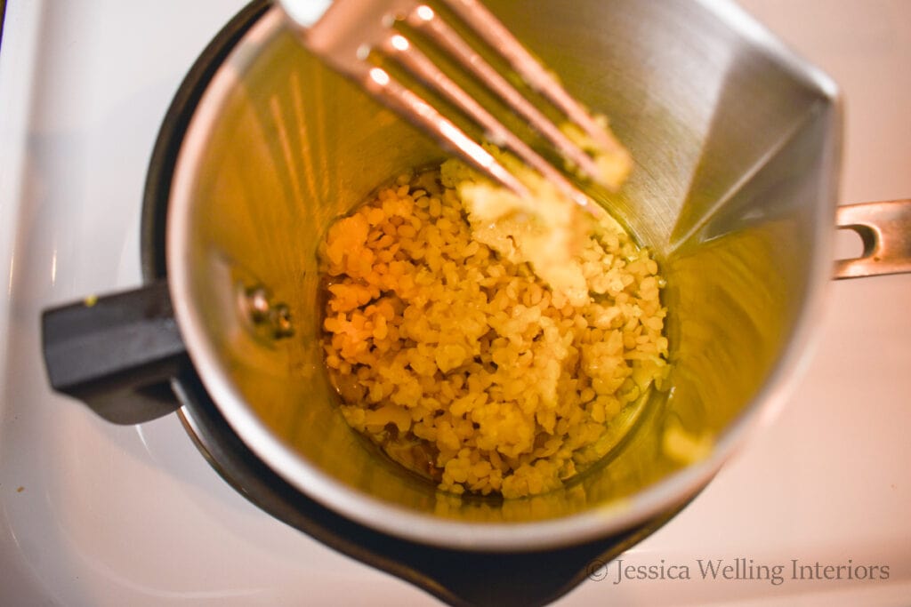 beeswax being melted in a double boiler and stirred with a fork