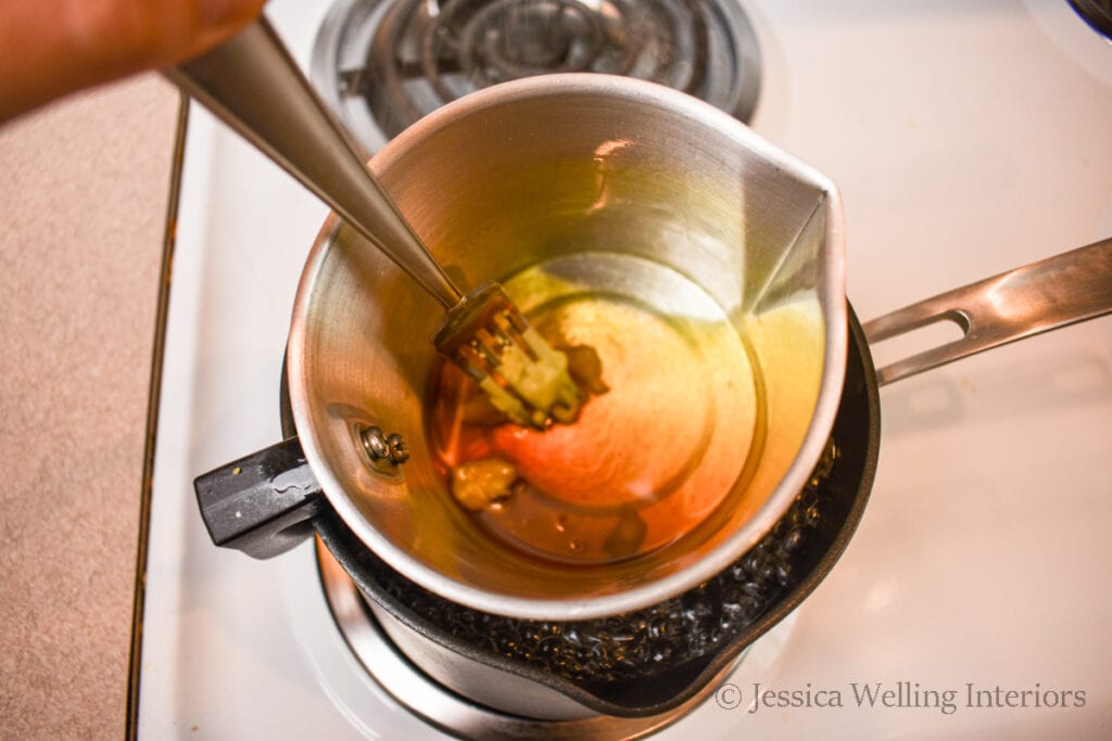 close up of melting beeswax in a metal pitcher on the stovetop