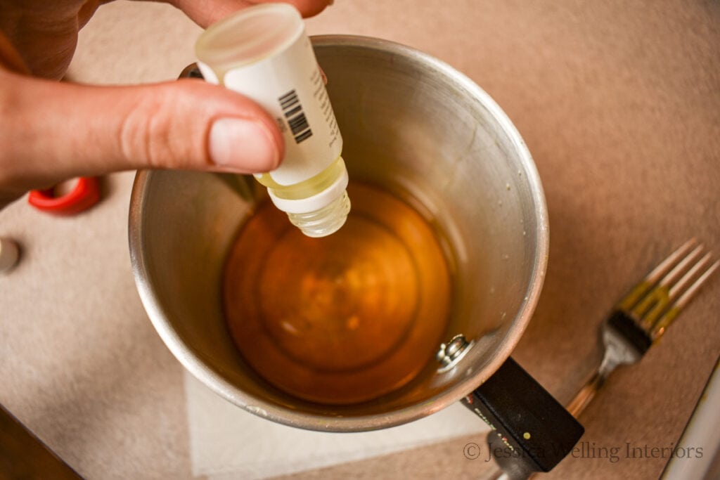candle fragrance oil being added to melted beeswax to make wax melts