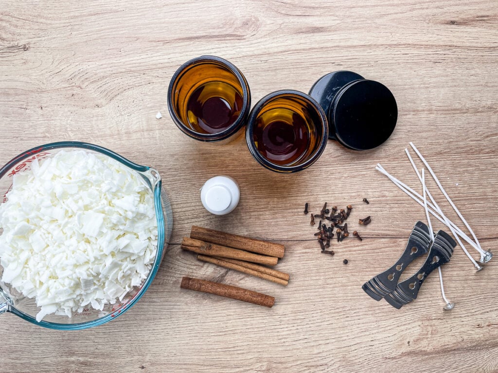 materials to make scented soy candles: candle jars, soy wax flakes, fragrance oil, wicks, centering devices, and cloves