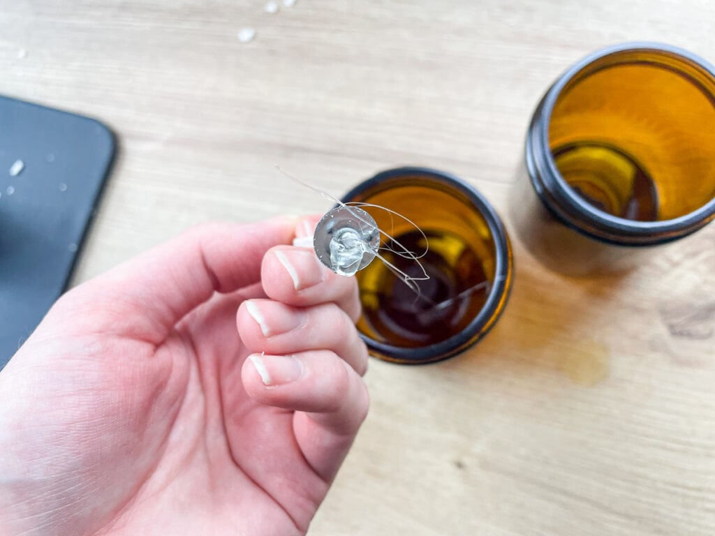 hand holding a wick upside down to show a glob of hot glue on the3 end of it