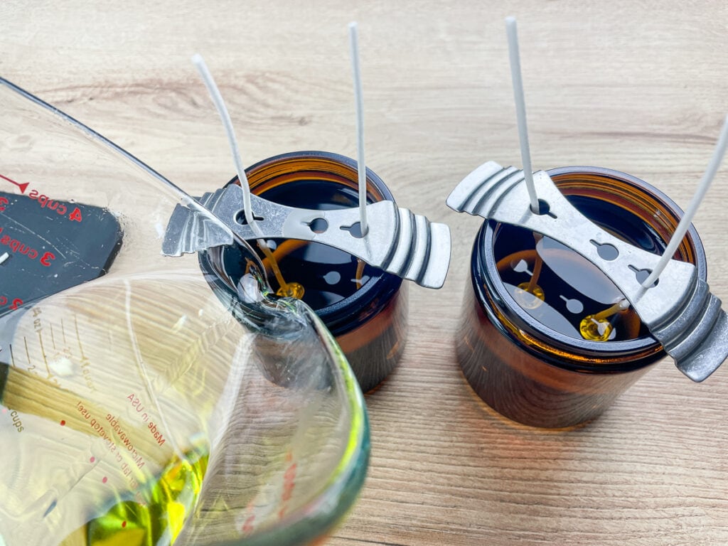 hot wax being poured into glass jars to make scented soy candles