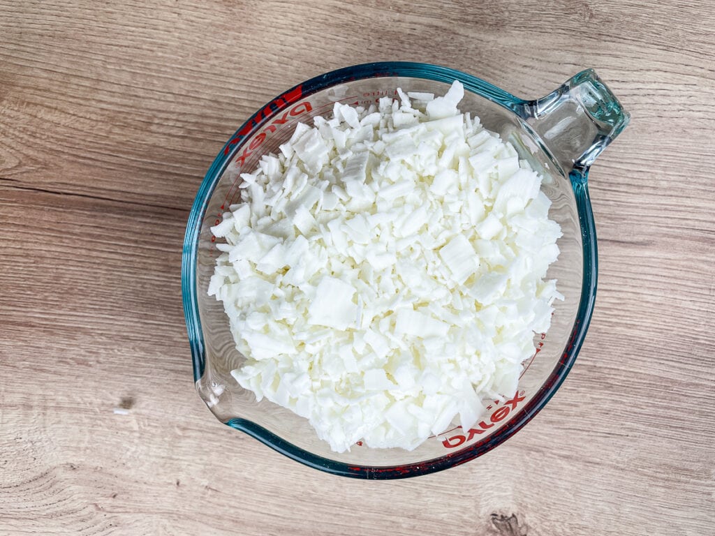 overhead view of large glass measuring cup full of soy wax flakes