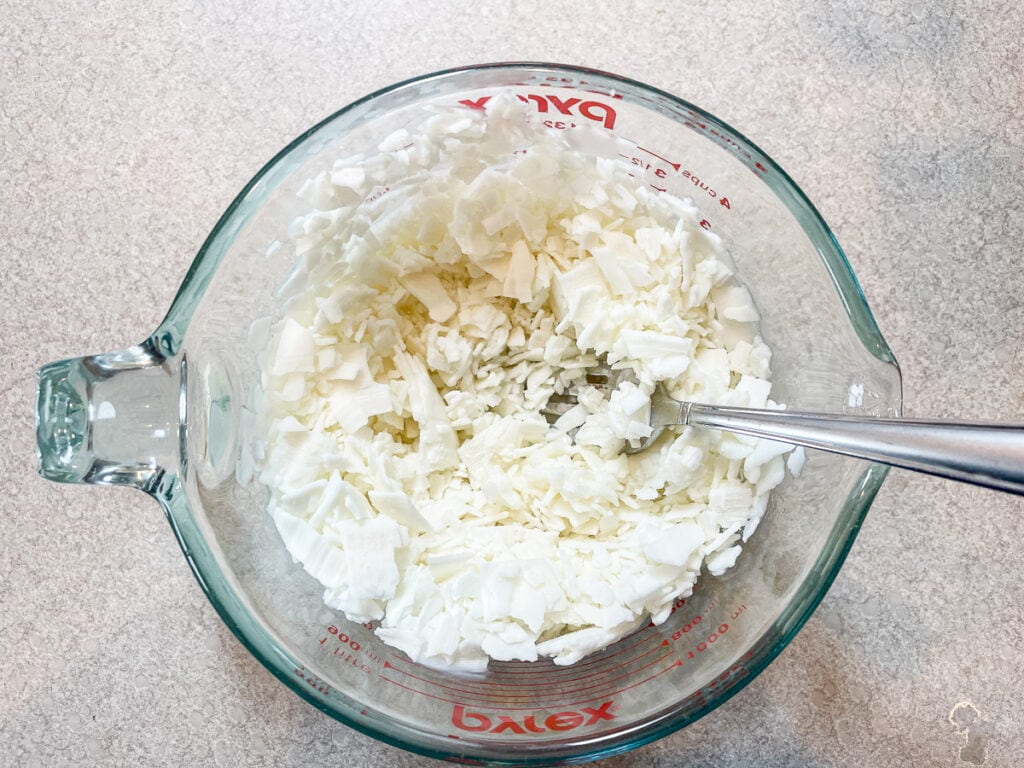glass measuring cup with partially melted soy wax flakes
