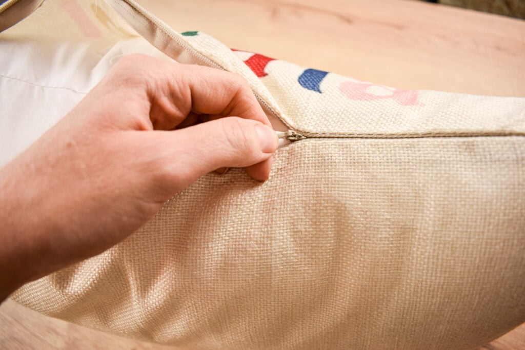 close up of hand zipping a Christmas throw pillow cover closed