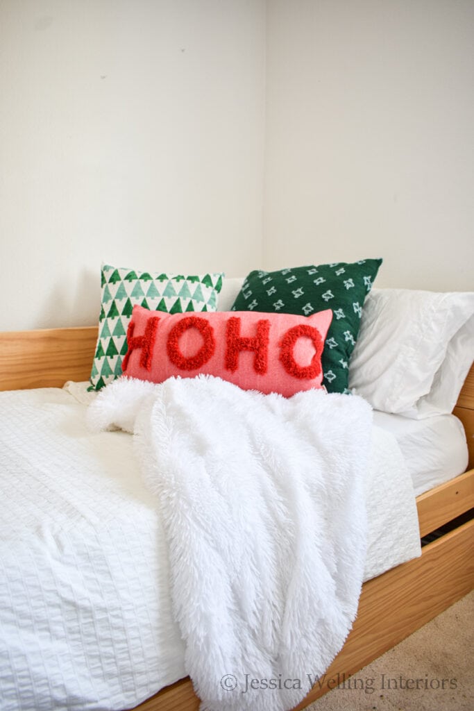 bed with a white faux fur Christmas throw blanket and Christmas pillows