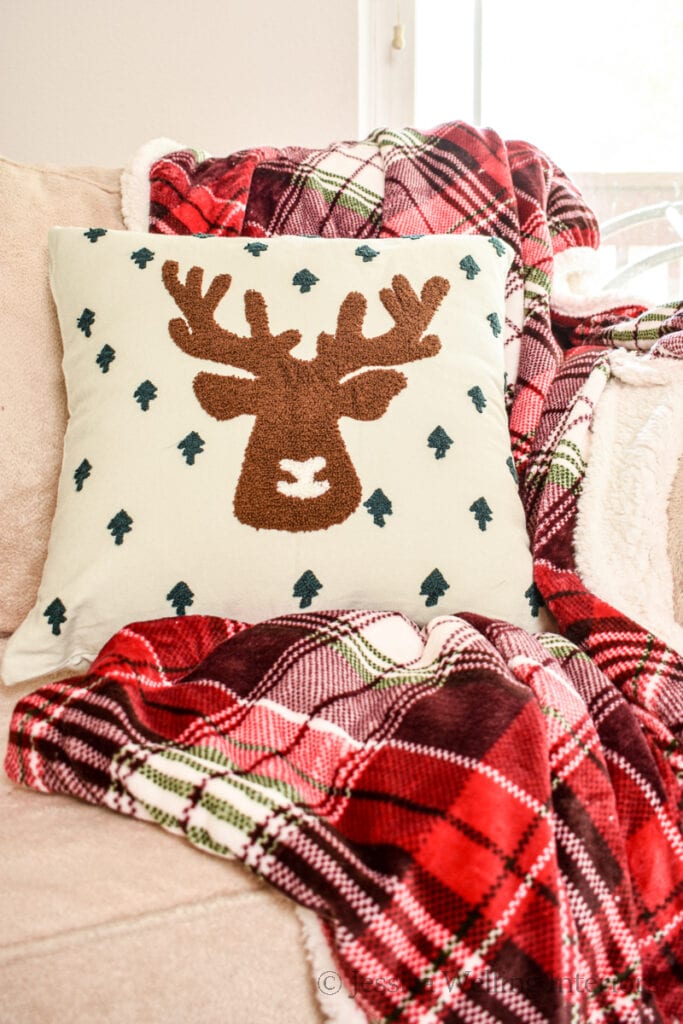 red plaid Christmas blanket draped over an armchair with a reindeer pillow