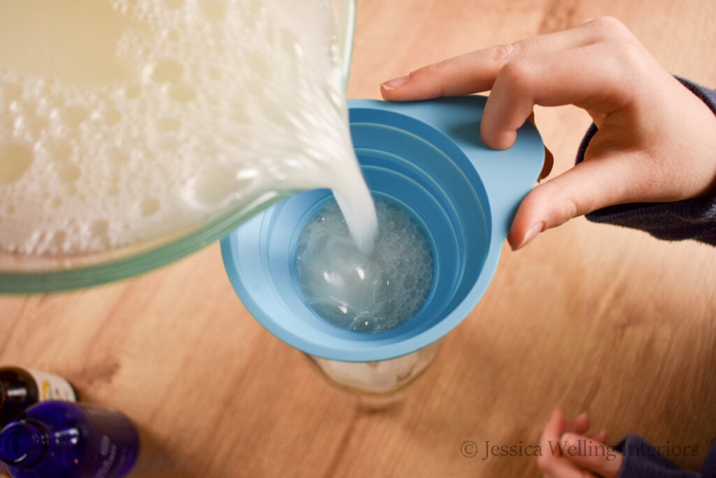 bubble bath being poured into a glass bottle using a funnel