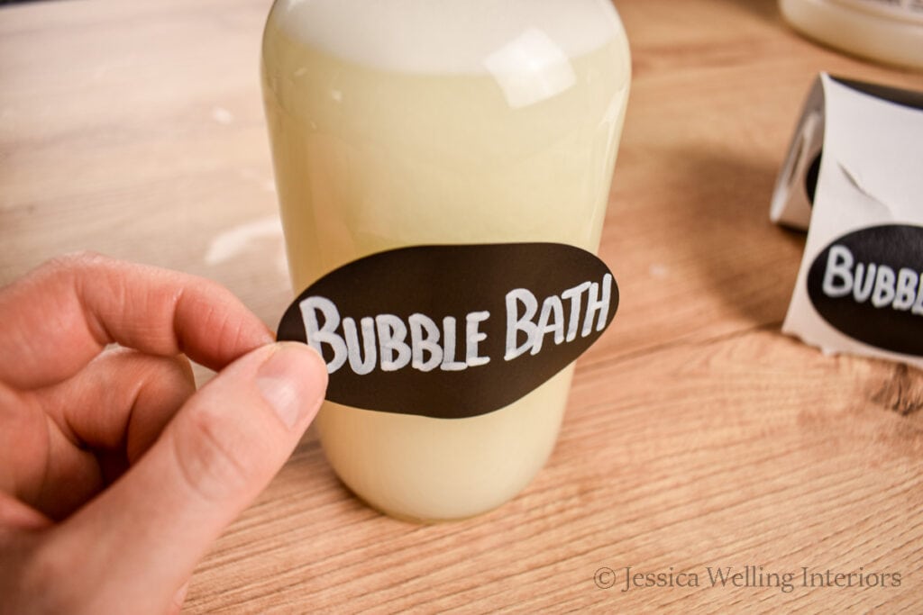 sticker label being applied to a glass bottle of homemade bubble bath