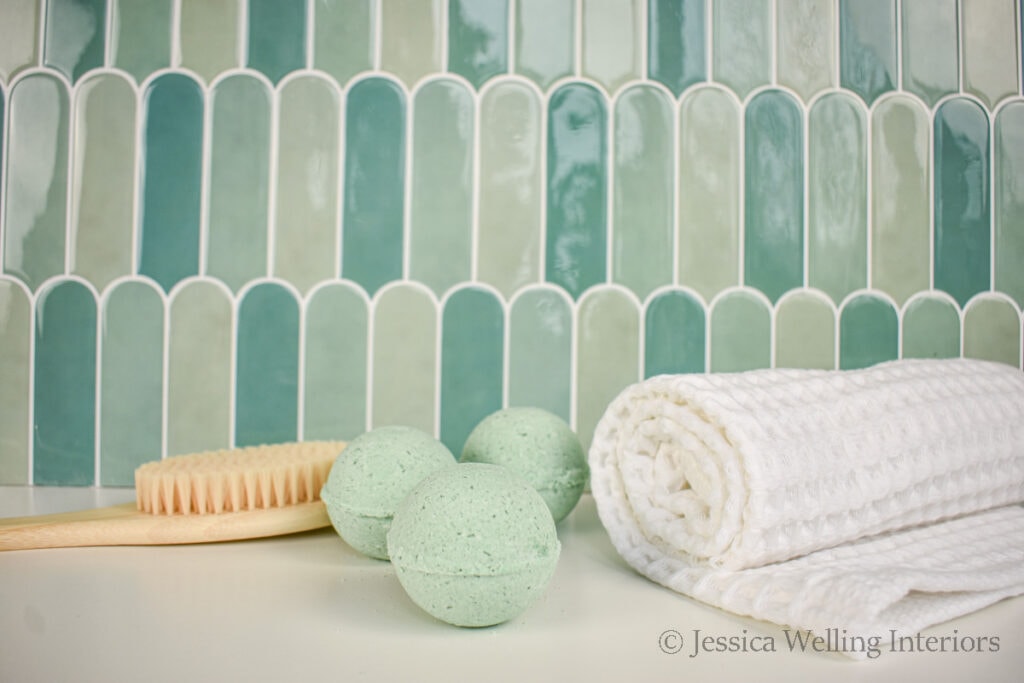 3 handmade bath bombs sitting on the edge of the tub with a white towel and brush