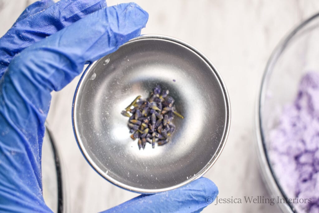 close up of one half of a bath bomb mold with a few lavender flowers in the bottom