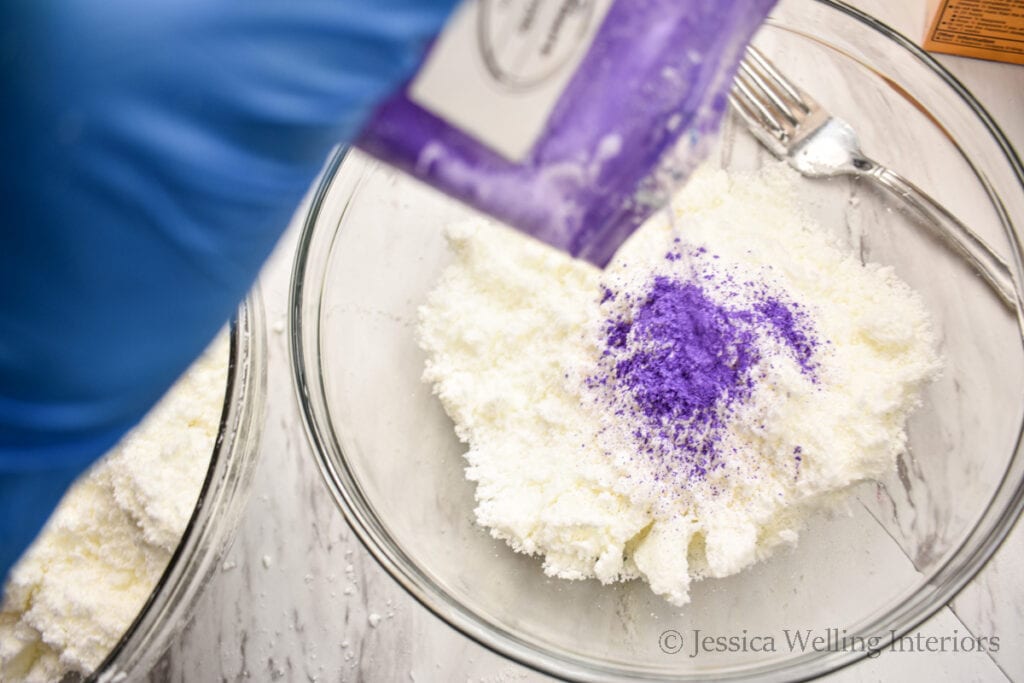 purple mica powder being added to a bowl of bath bomb mixture