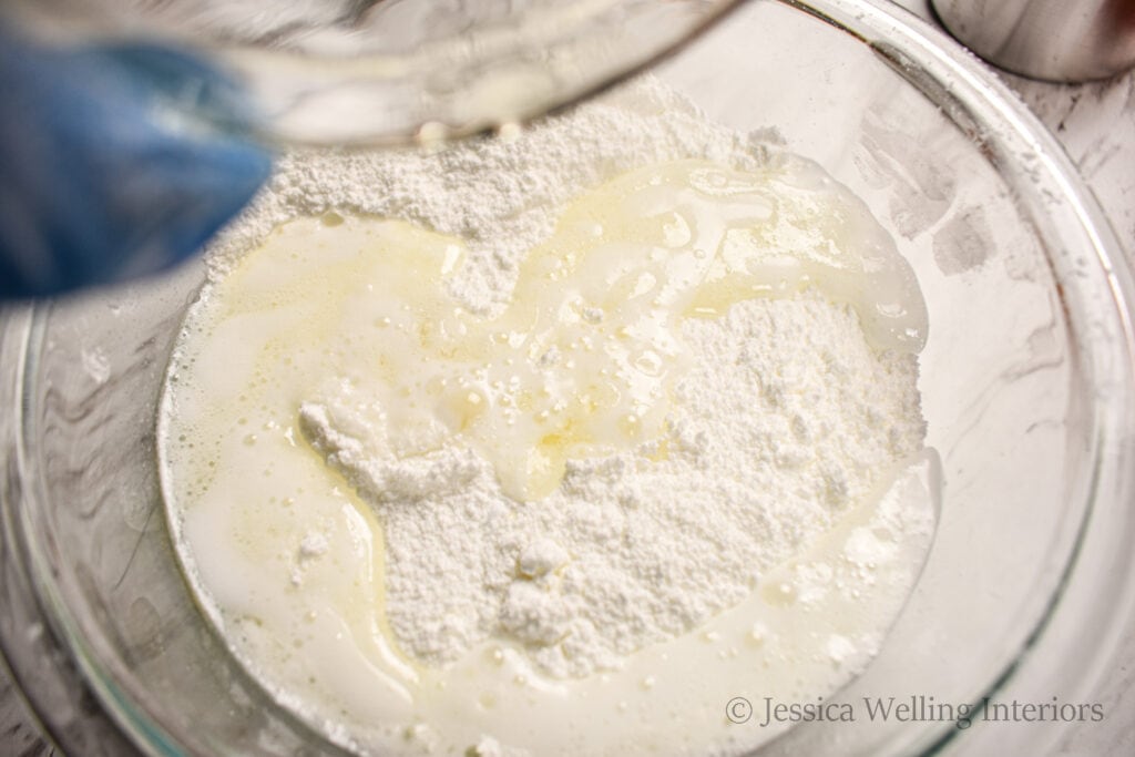 wet ingredients being poured into dry ingredients to make DIY bath bombs