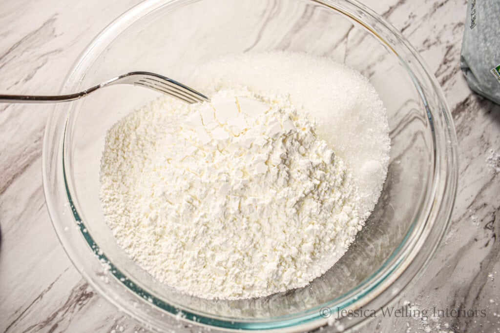 overhead view of a mixing bowl with all the dry ingredients for bath bombs and a fork