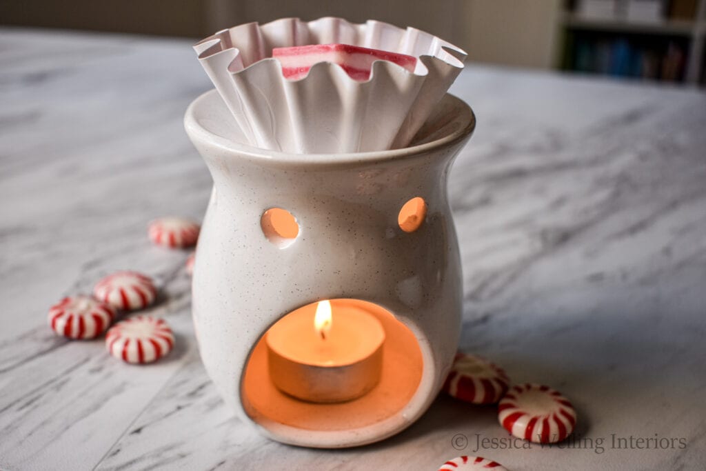 white wax burner with a tealight candle burning inside it and peppermint scented wax melts in the melting cup