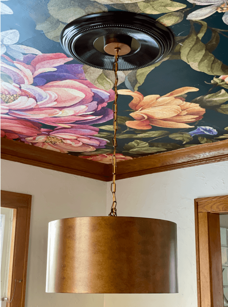 dining room ceiling covered with a floral wallpaper mural and a chandelier