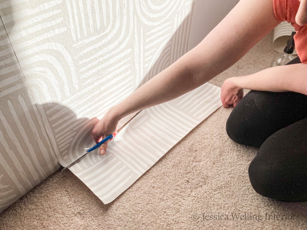 bottom of a run of wallpaper being trimmed with scissors