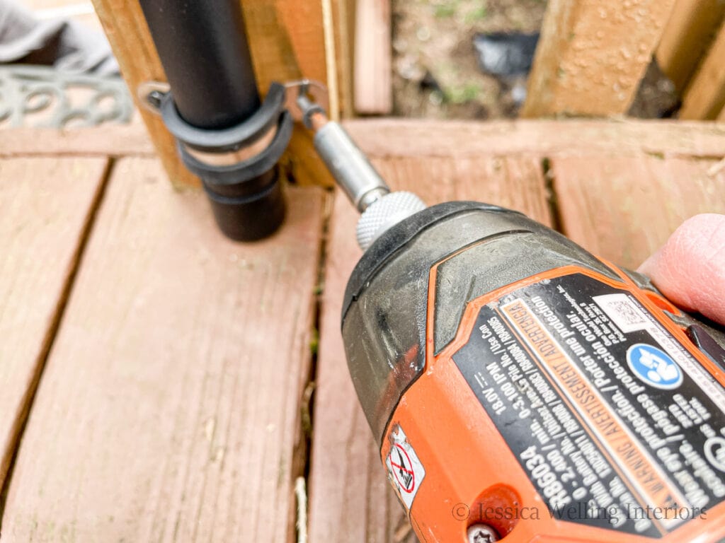 close-up of a string light pole being attached to a deck railing with a metal bracket