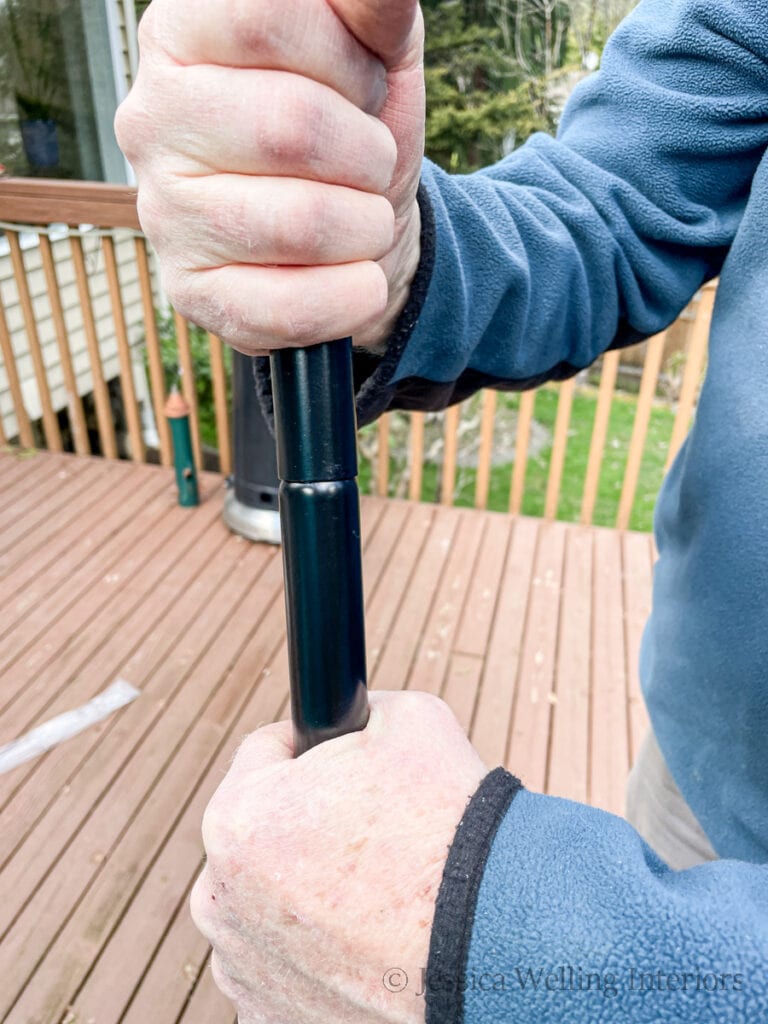 close-up of hands attaching two sections of a metal string light pole together to assemble it