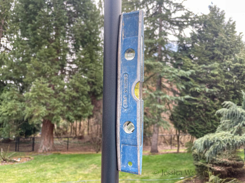 close-up of a string light pole with a magnetic level attached to the side of it