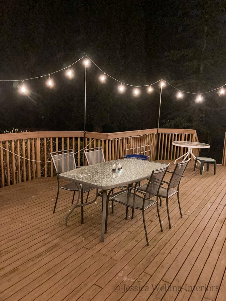 nighttime photo of deck with string lights hanging from string light poles attached to the deck railings 
