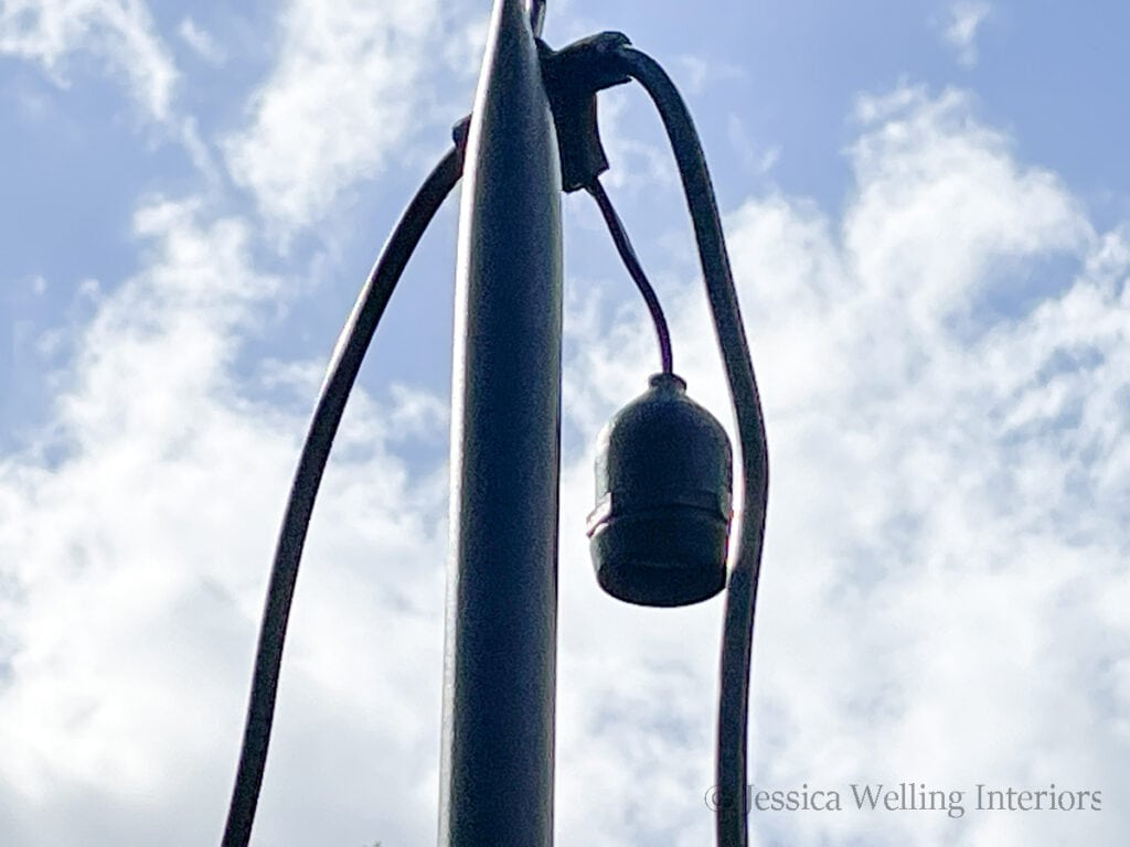 close-up of the top of a string light pole  with light cord draped over it, but without lightbulbs