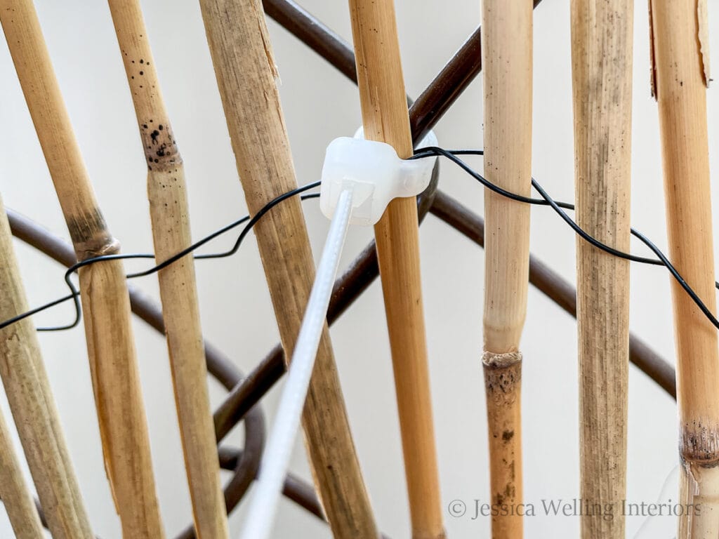 close-up of a zip tie attaching a bamboo privacy screen to a chain link fence