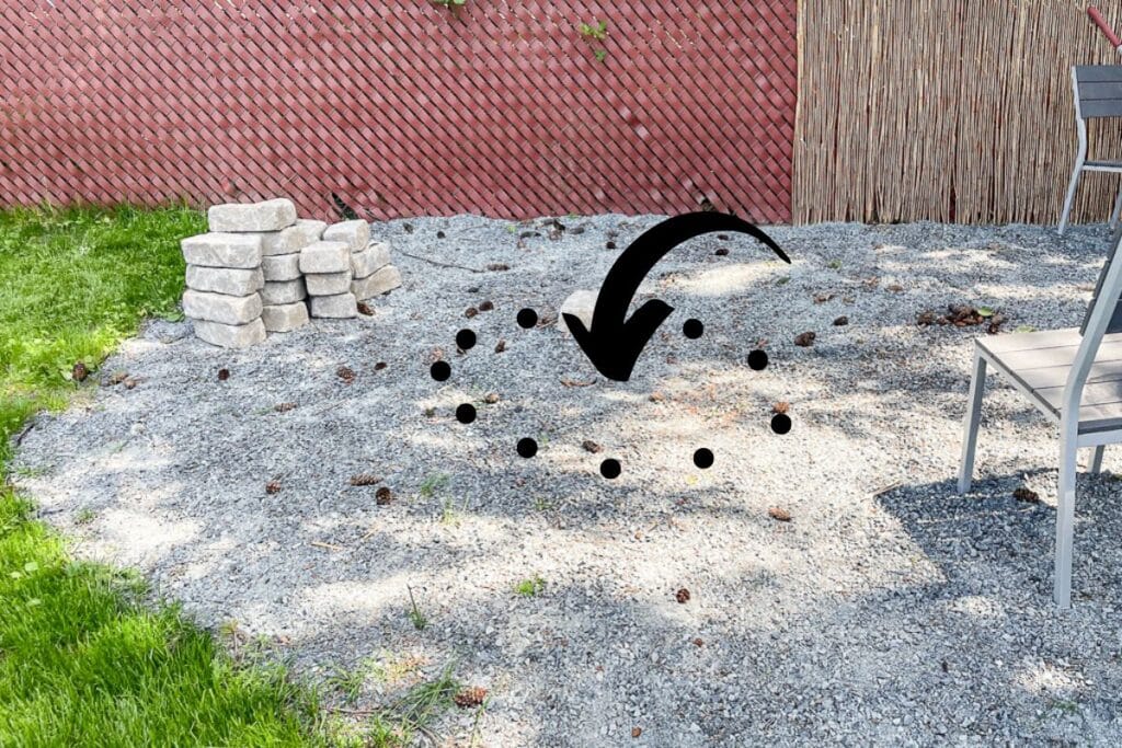 photo of a gravel patio with an arrow showing the location where the new DIY fire pit will be built