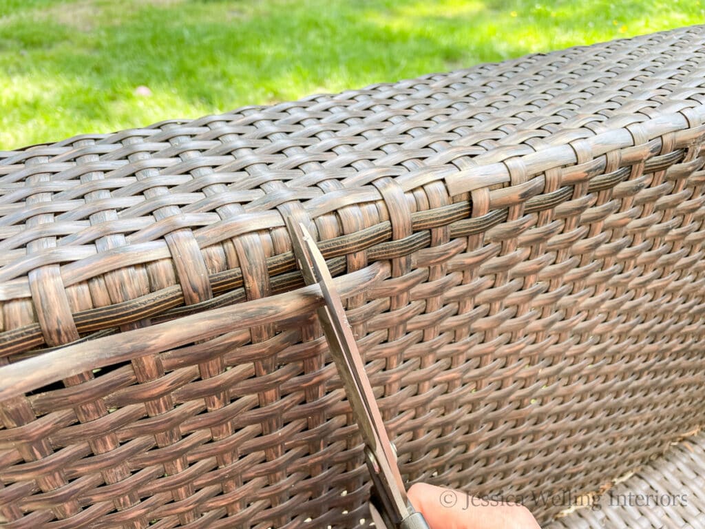 scissors cutting a damaged reed from a piece of wicker outdoor furniture
