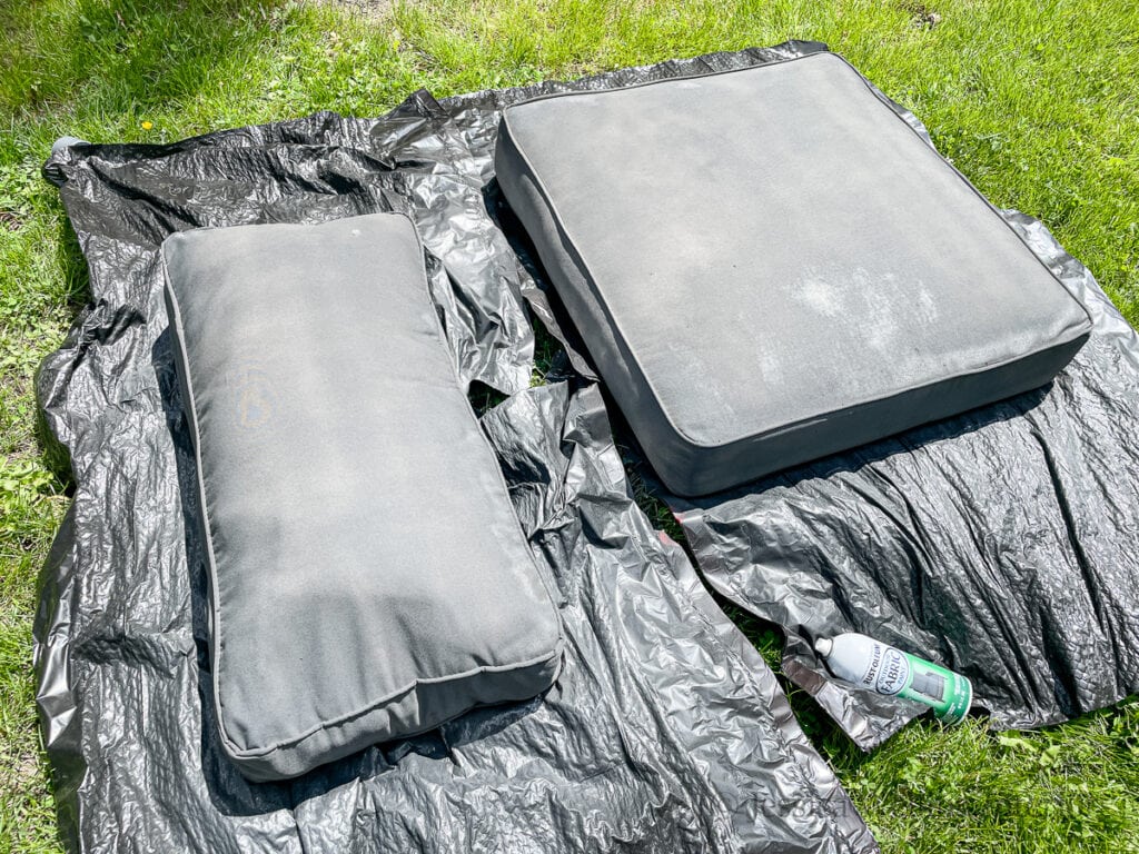 two outdoor cushions painted gray and drying in the grass