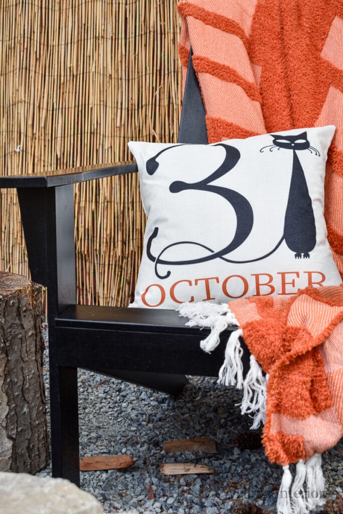 outdoor chair with an orange throw blanket and Halloween pillow