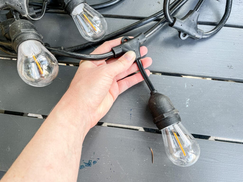 hand holding one of the sockets on a string of Feit Electric LED string lights