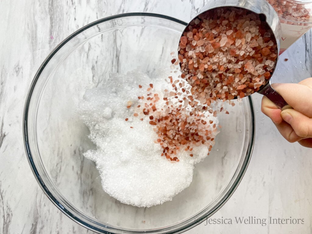 overhead view of pink Himalayan salt crystals being poured into a glass bowl