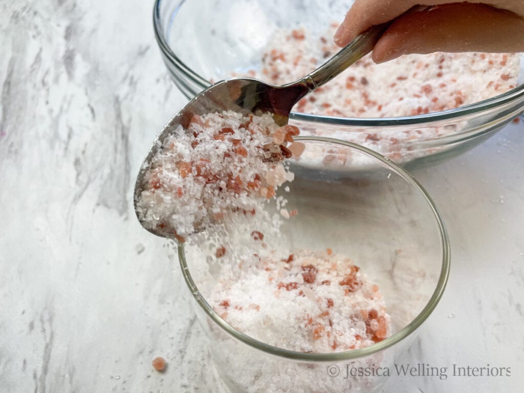 spoon filling a glass jar with finished Himalayan salt bath