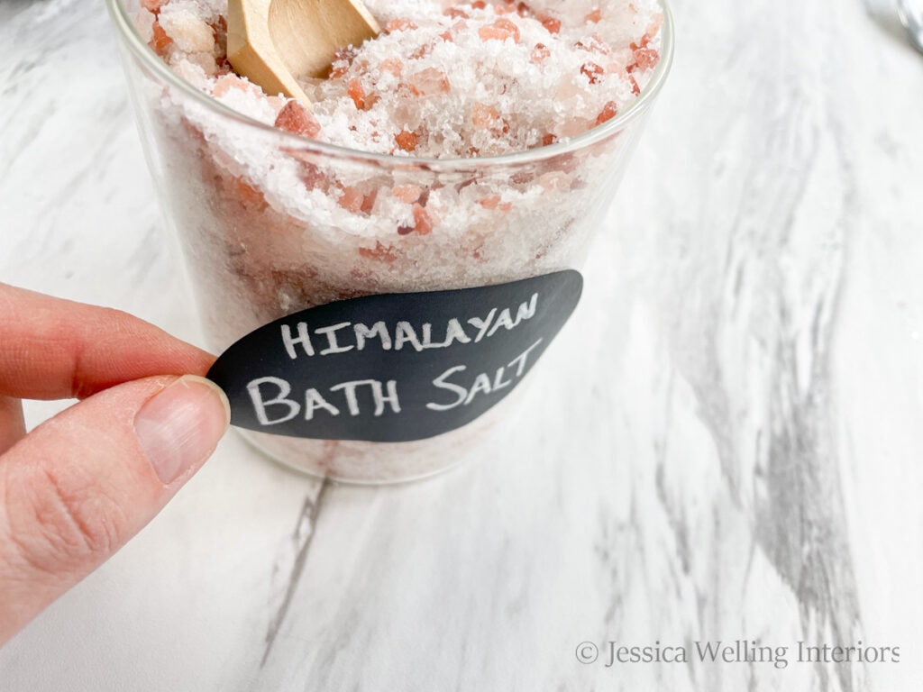 chalkboard sticker label being applied to a glass jar of homemade Himalayan bath salt