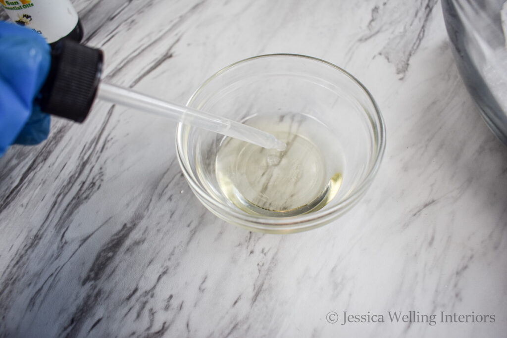 essential oils being added to a bowl of carrier oil with an eye dropper