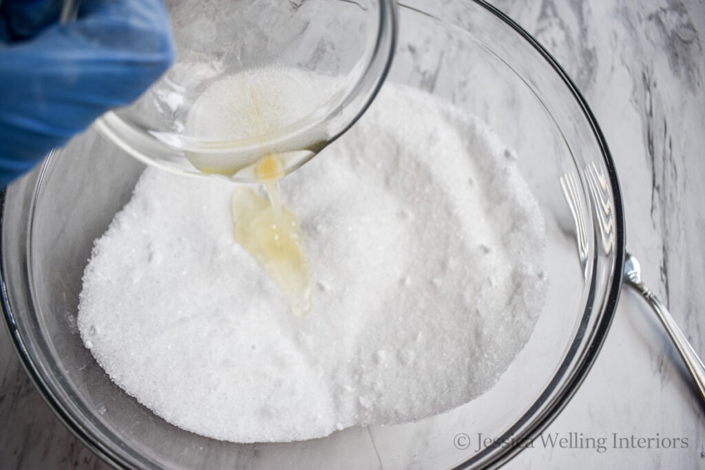 oils being poured into a bowl of bath salt mixture