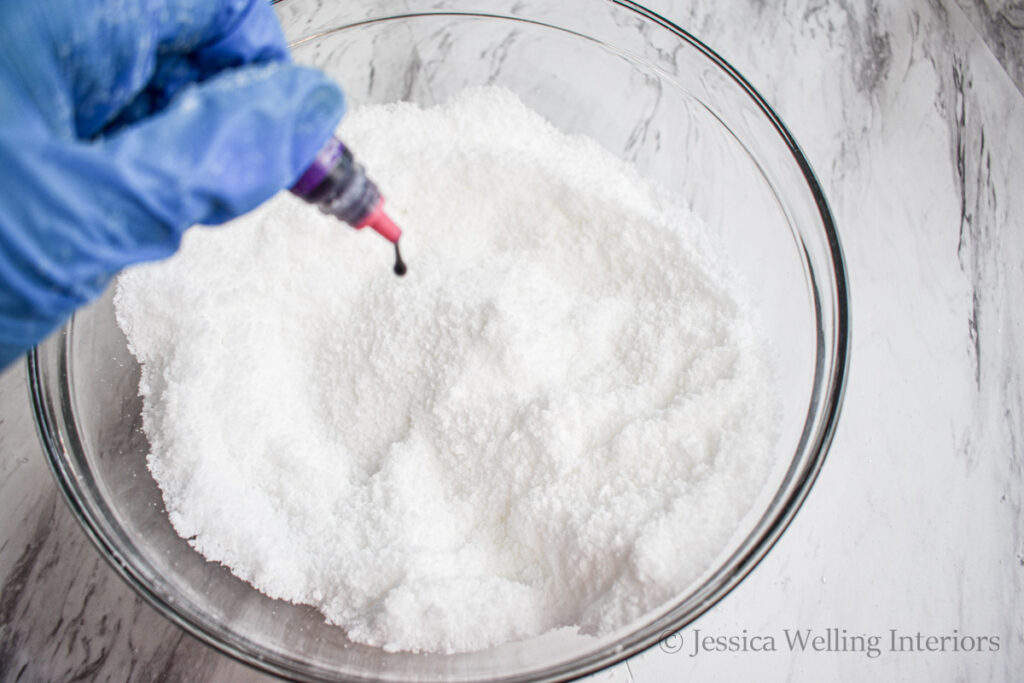 food coloring being added to a bowl of homemade bath salts