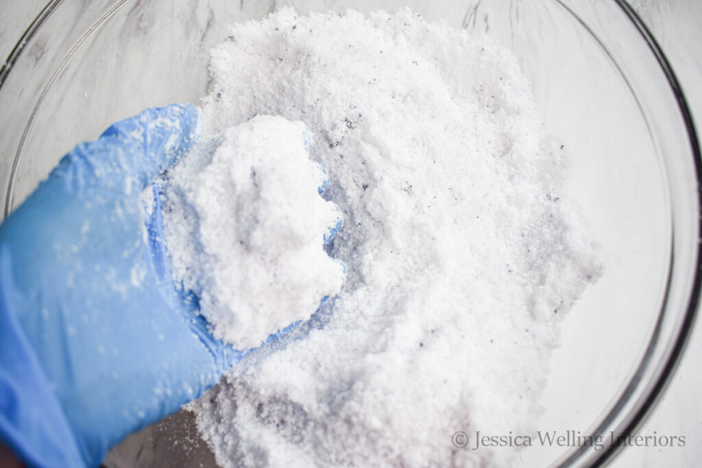 gloved hand mixing bath salts in a mixing bowl